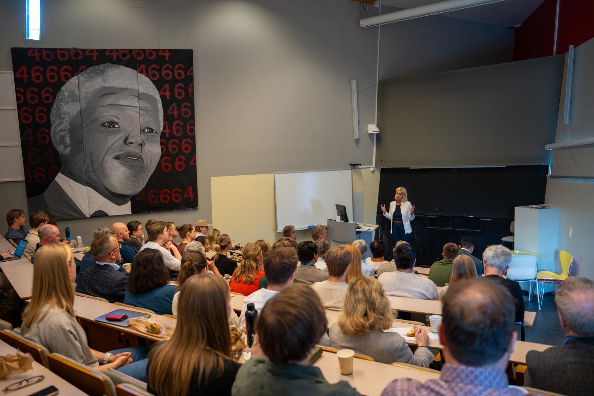 Person står i auditorium og taler foran publikum.