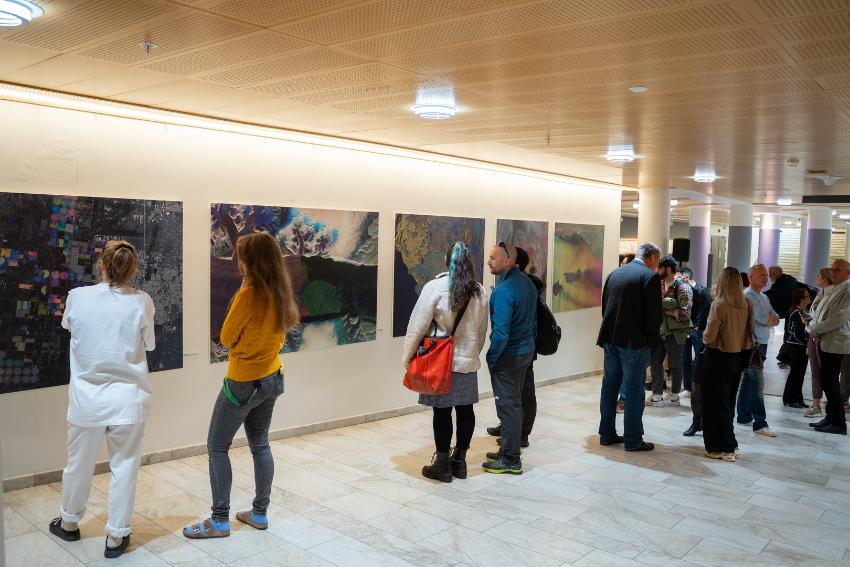 Bildet viser fotografier fra utstillingen med mennesker i forgrunnen.