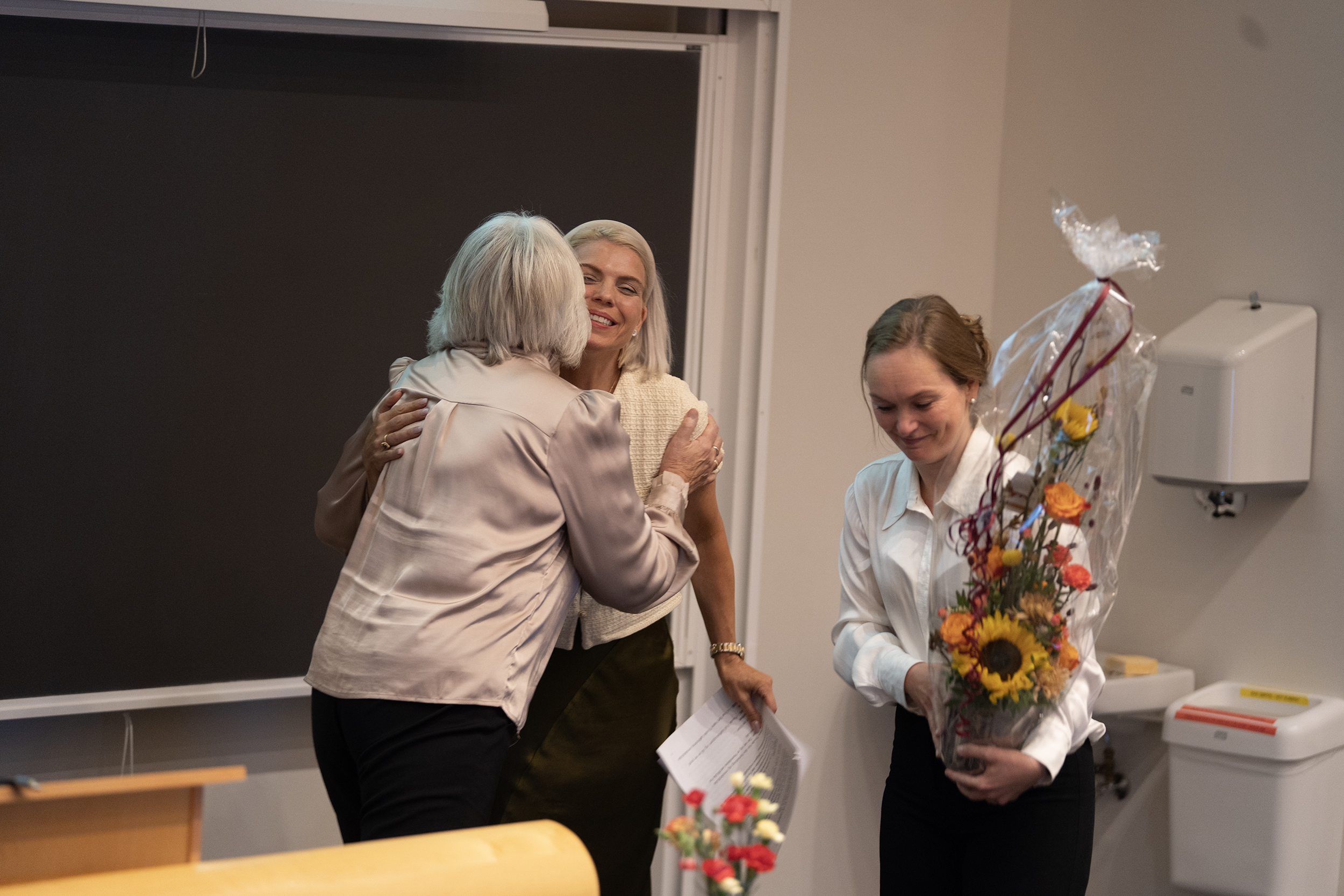 En kvinne leverer blomster til en annen. 