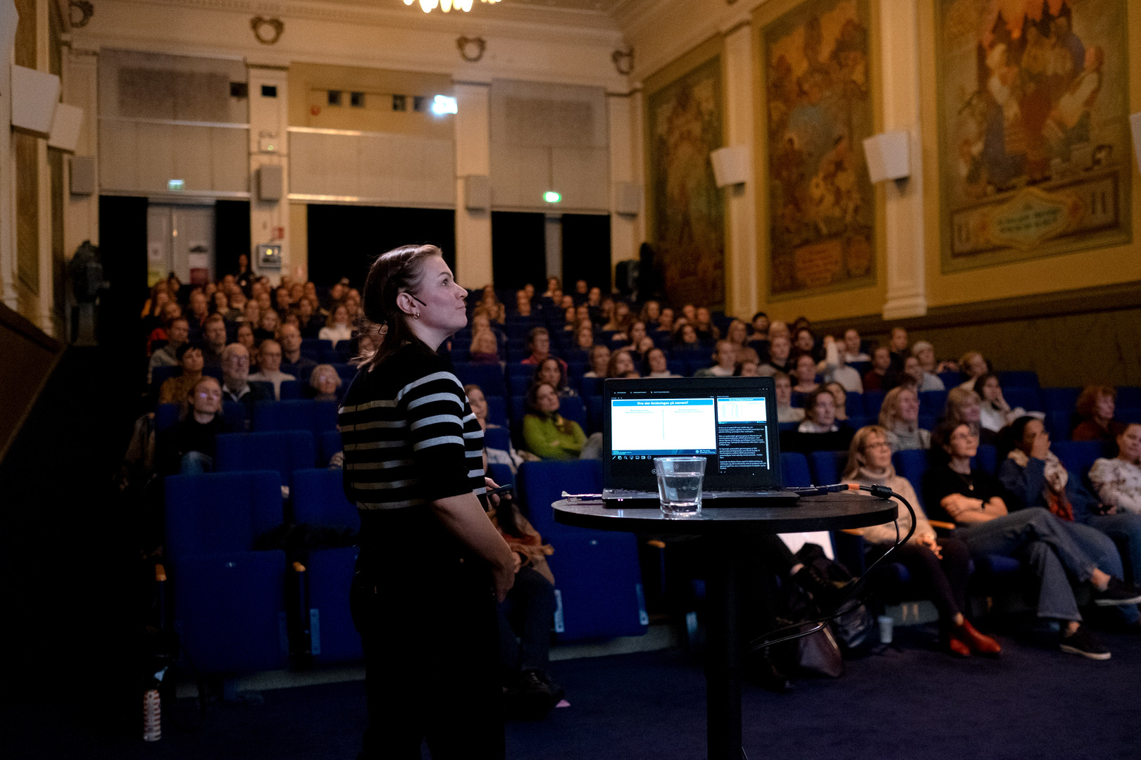 dame som holder foredrag foran mange folk