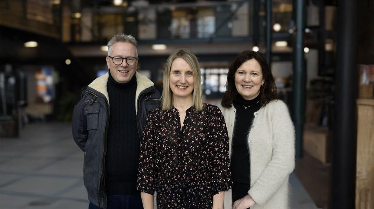De tre artikkelforfatterne står i foajeen ved UiT i Harstad og ser inn i kamera