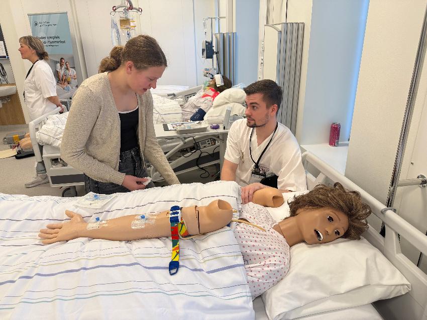 Sykepleierstudent viser på en dukke hvordan en elev skal sette en veneflon