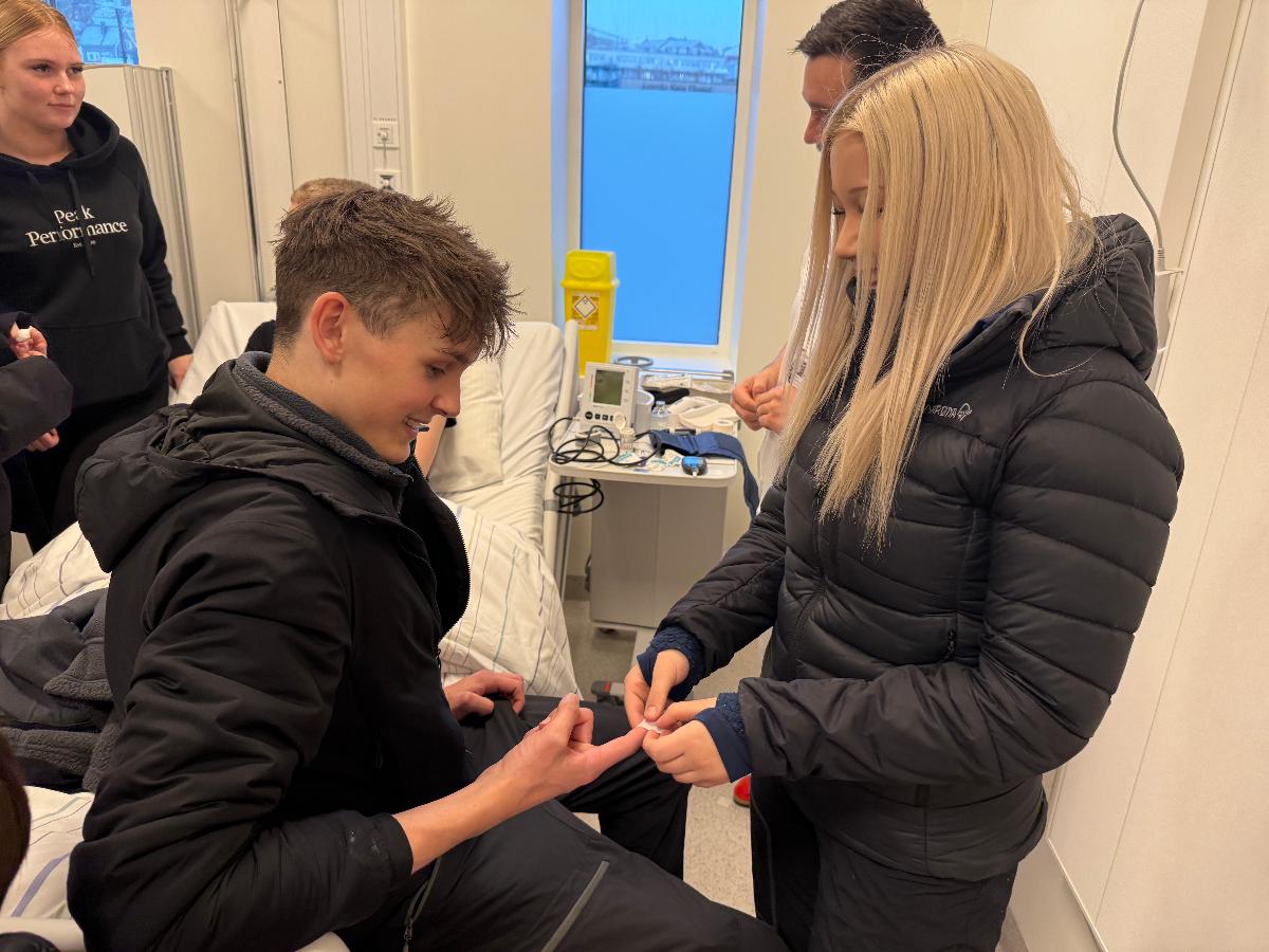 Aurora Louise Eriksen måler blodsukkeret til Audun Rikstad Rønning. Begge fra Breilia skole i Hammerfest
