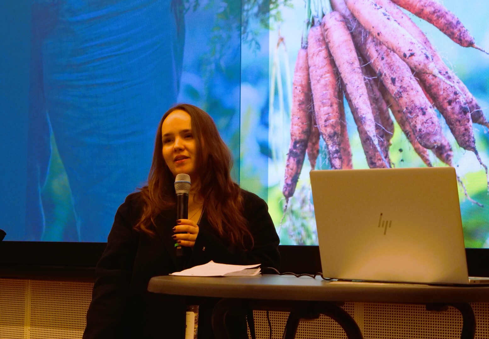 Kvinne taler foran en skjerm.