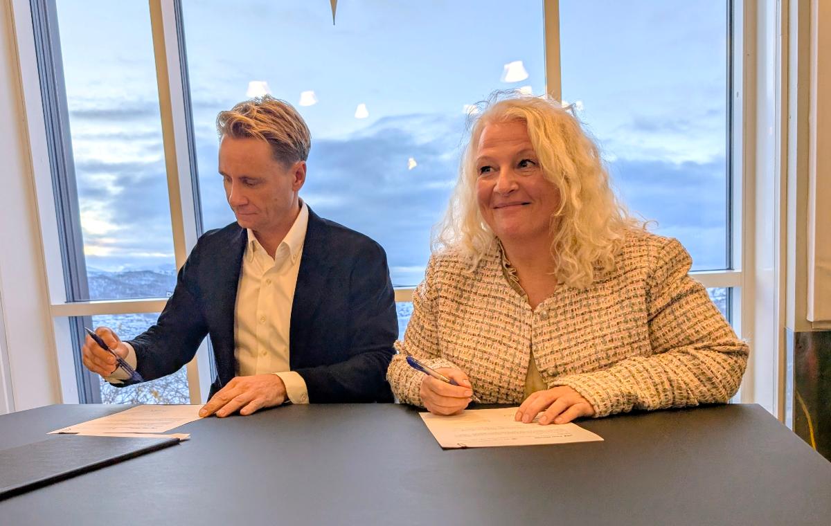 To personer sitter evd bord og signerer på avtale