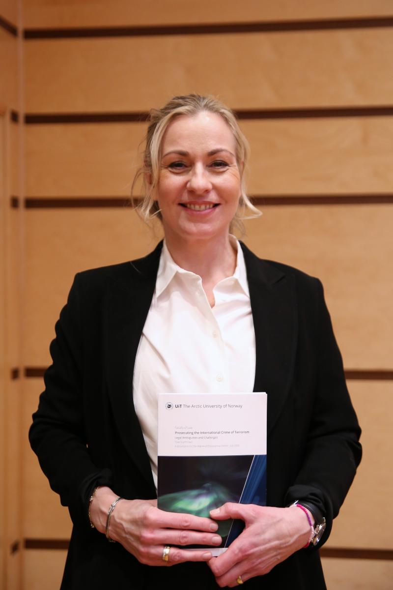 kvinne smiler, holder bok