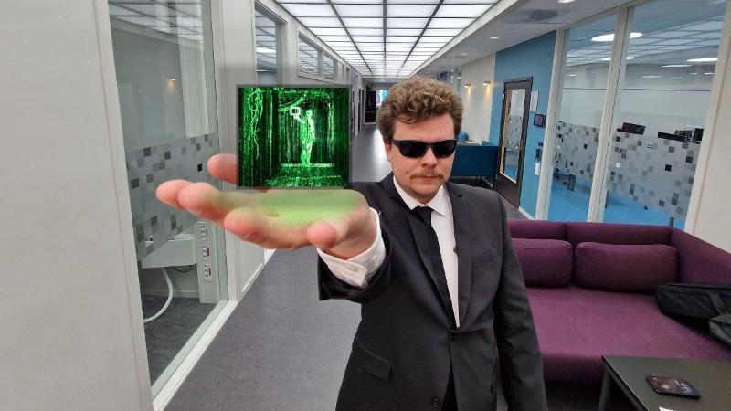 mann som holder lysende dings, han har dress og solbriller p&aring;