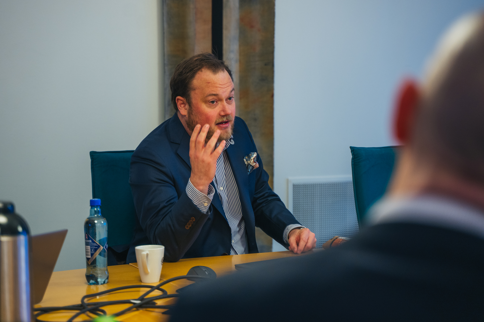 Mann sitter p&aring; sitt kontor og prater engasjert. 