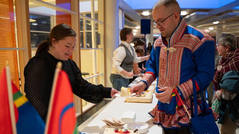 dame som gir kake til en mann med samisk kofte