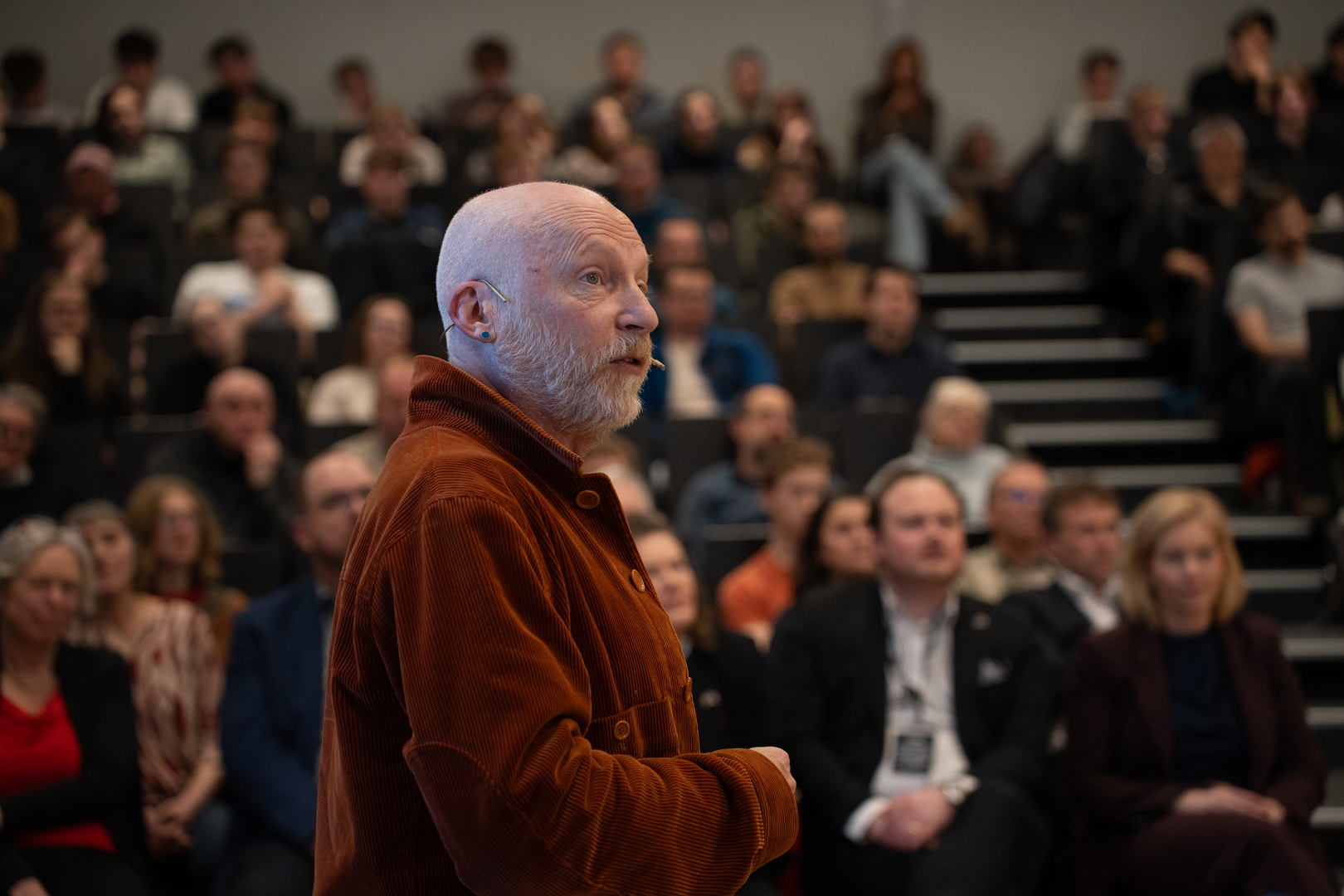 mann som snakker i mikrofon med masse publikum i bakgrunnen