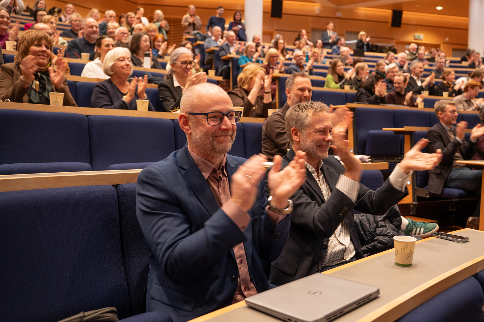 Publikum applauderer i auditorium