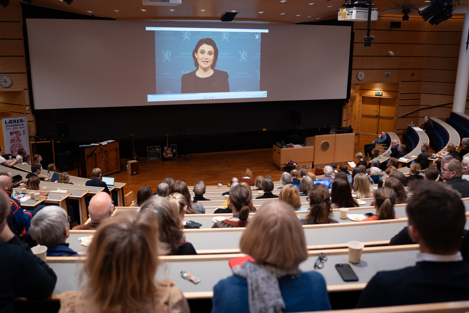 Kvinnelig minister taler p&aring; storskjerm