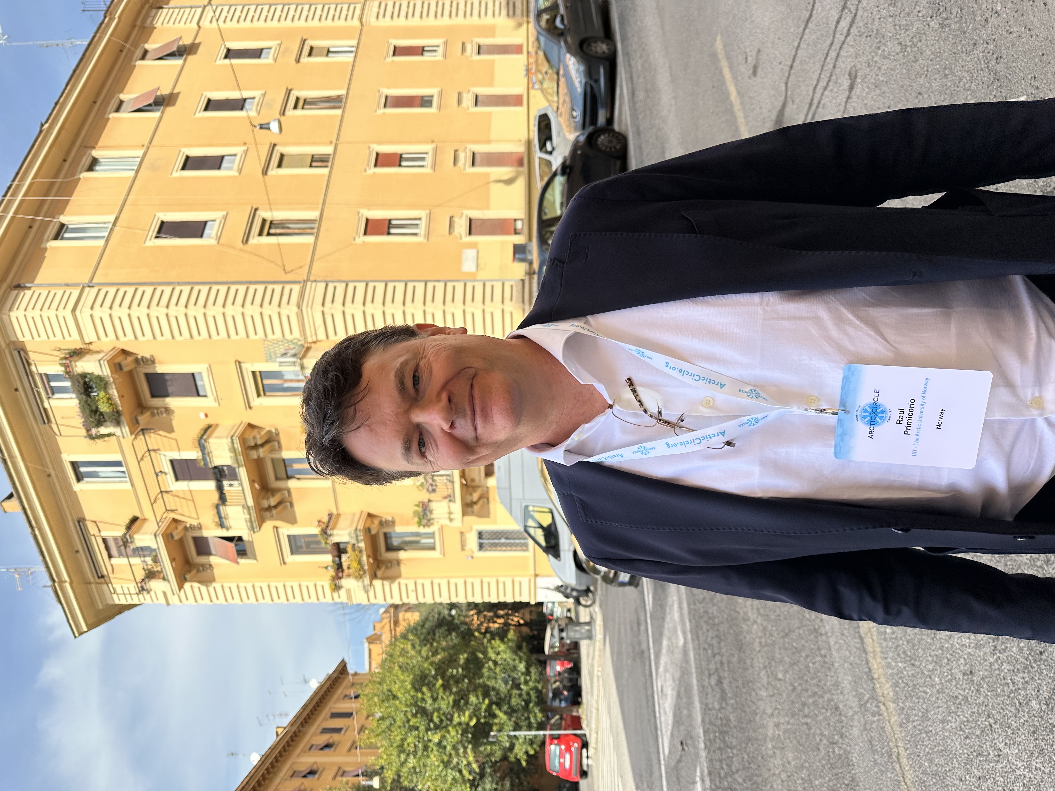 mann som st&aring;r p&aring; gata med et gult bygg bak