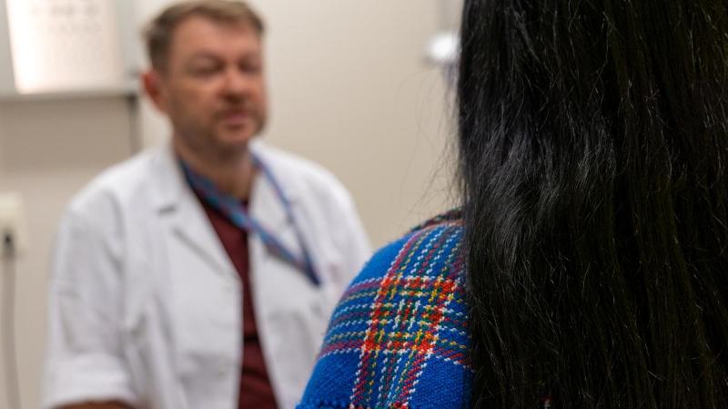 dame med samisk sjal som snakker med lege