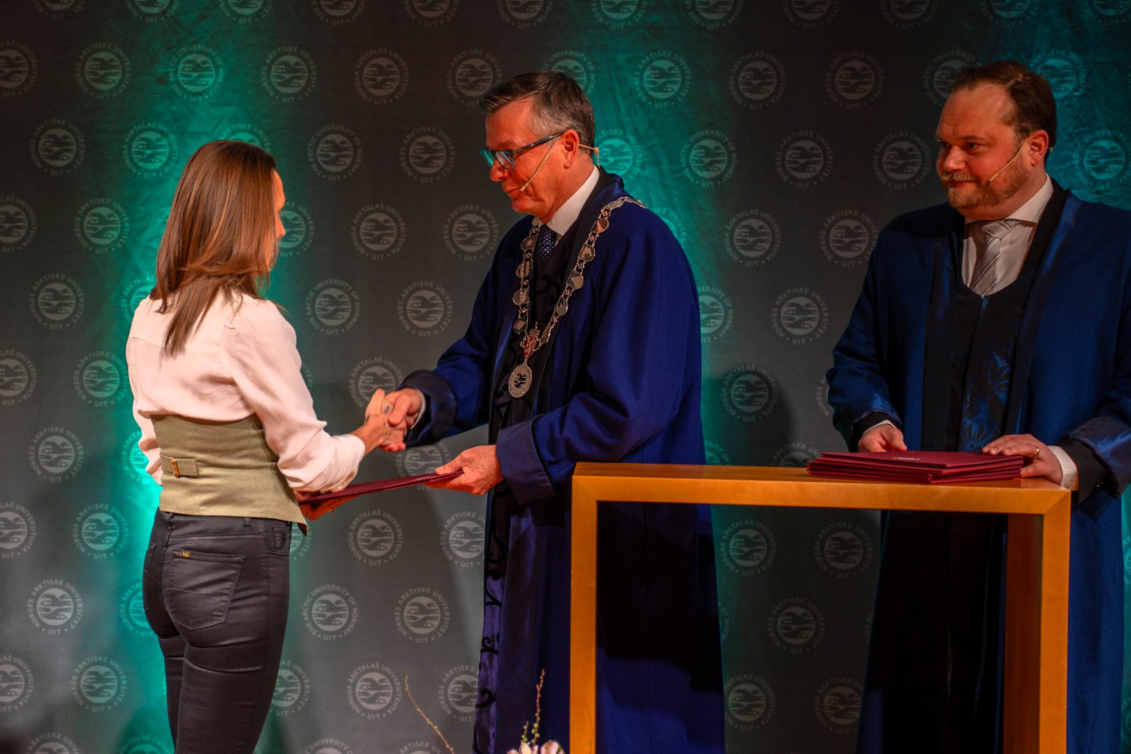 To seremonimestere deler ut diplom til kvinnelig doktor. 