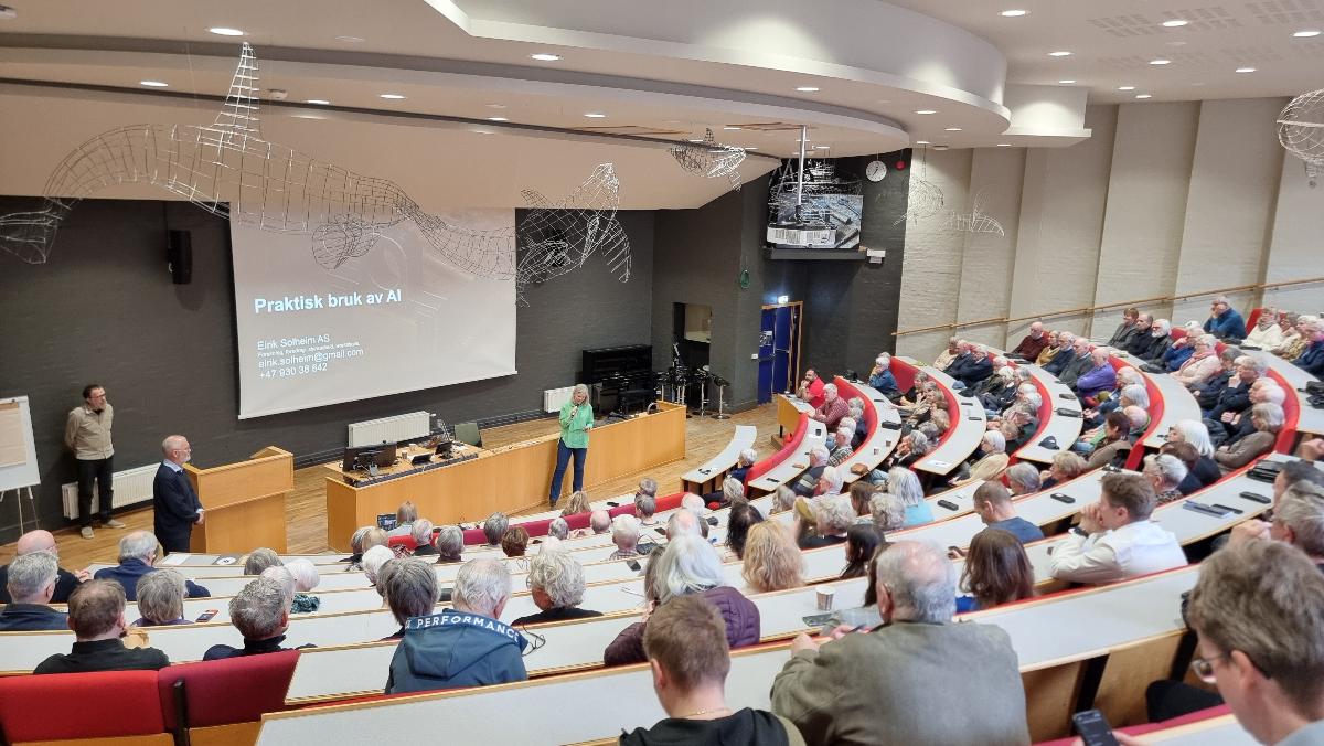 Stort auditorium med folk og foredragsholder foran