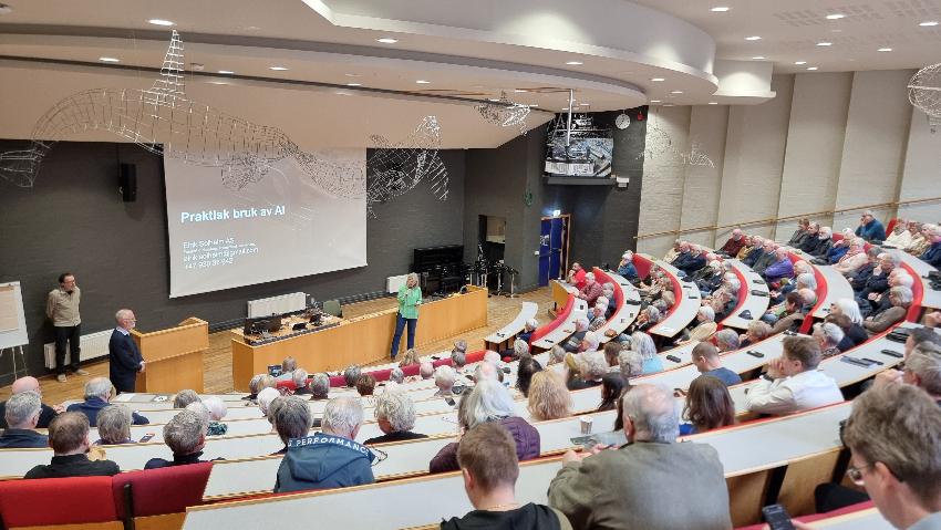 Stort auditorium med folk og foredragsholder foran