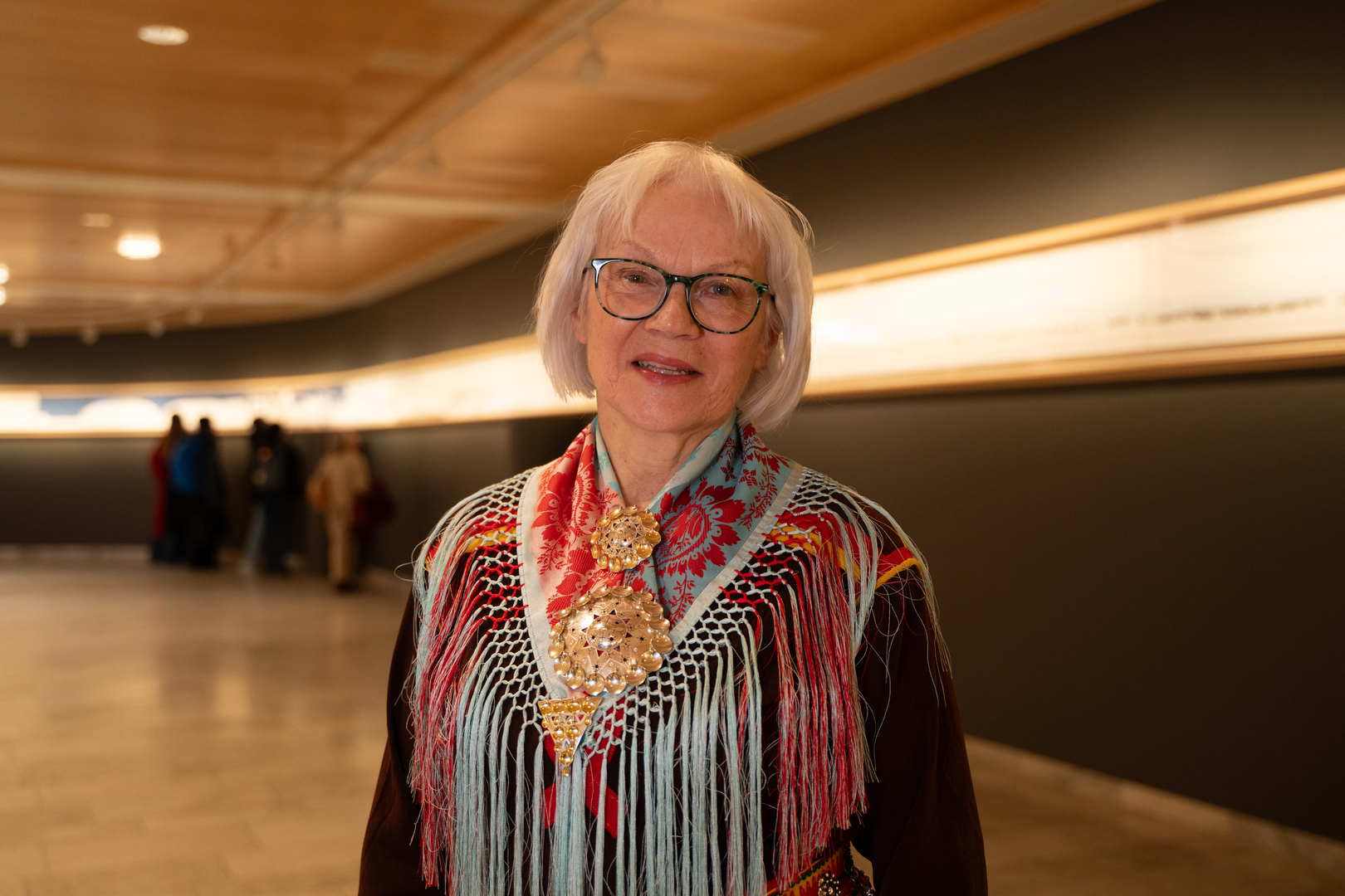 dame med kofte som st&aring;r foran kunstverk