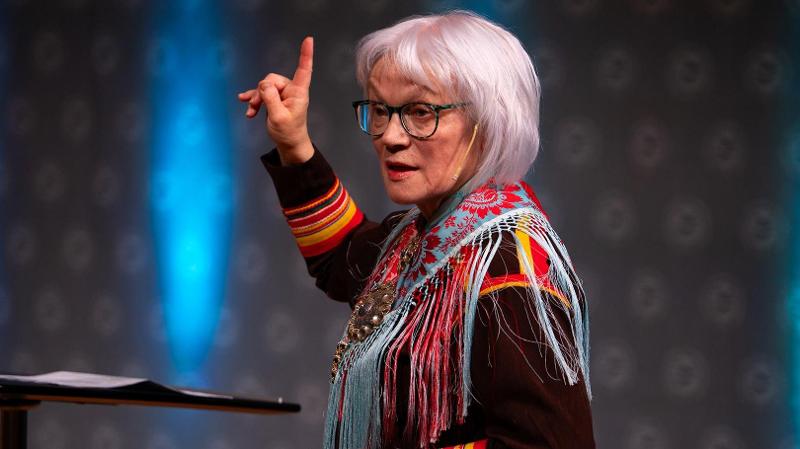 dame med kofte som st&aring;r p&aring; en scene 