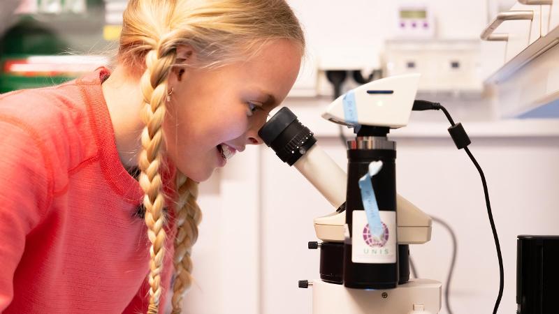 jente som ser i mikroskop