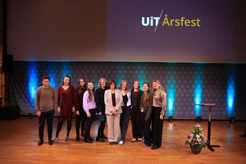 IMG_1825-2.jpg flere personer står samlet i en gruppe, smiler til kamera, æresdoktor står i midten, på en scene