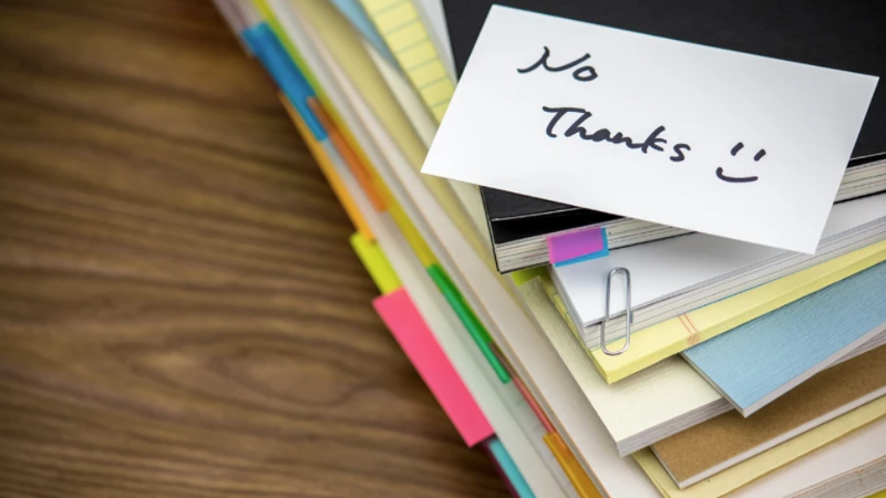 books and papers in a pile with a note that says no thanks on top