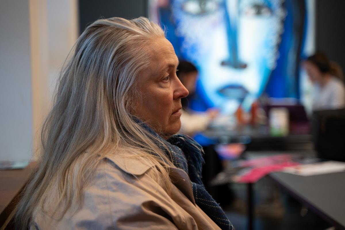 Alvorlig kvinne med karakteristik bl&aring;tt maleri i bakgrunnen. 