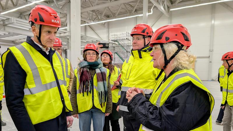 mennesker med hjelm og gul vest inni en hall