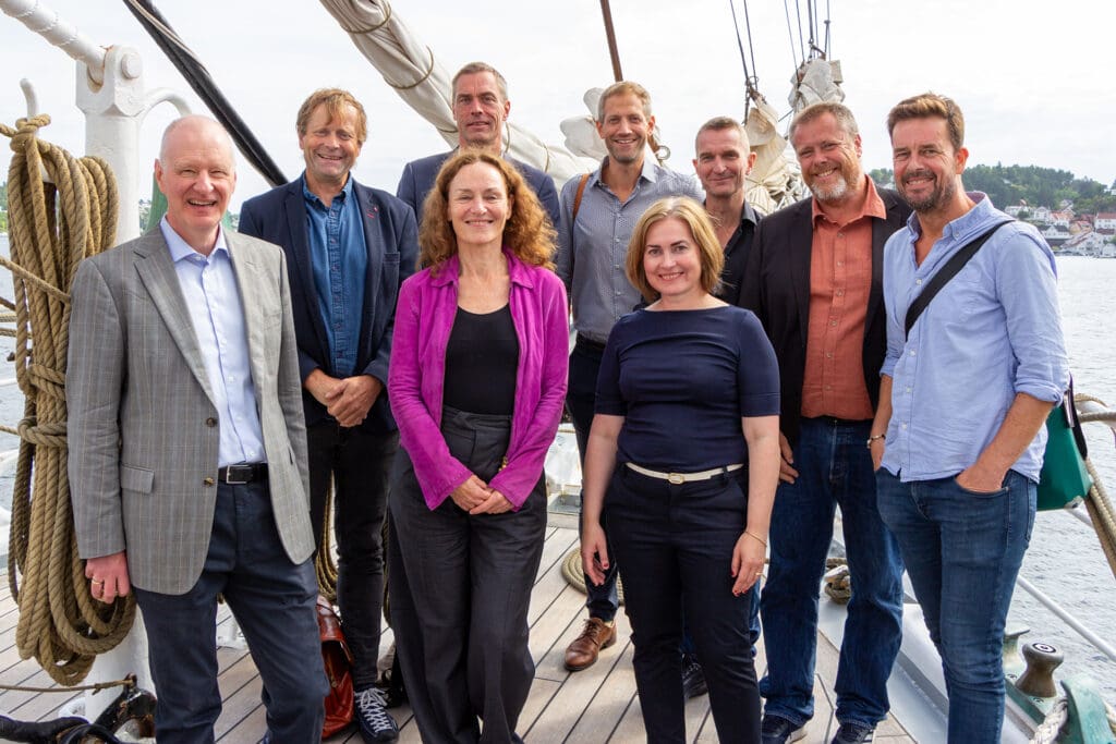 many people standing together on an old wooden sail boat