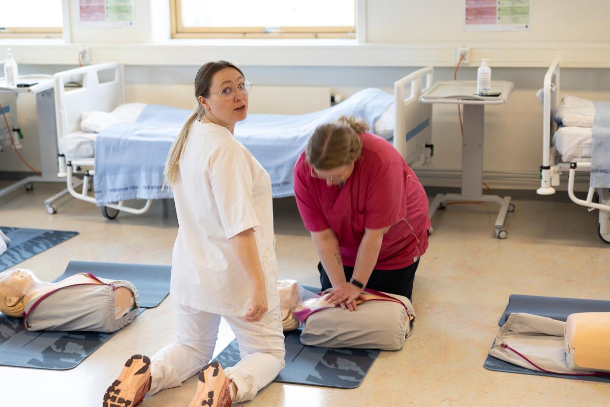 To personer &oslash;ver p&aring; hjerte-lungeredning p&aring; en Anna-dukke