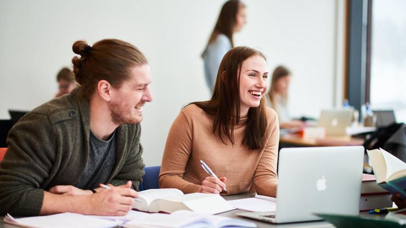 to studenter som sitter og jobber med studiene med papirer, b&oslash;ker og PC