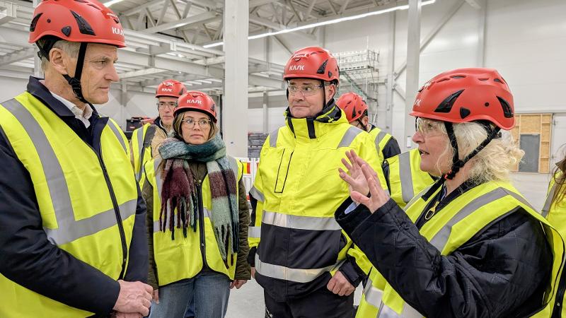 mennesker med hjelm og gul vest inni en hall