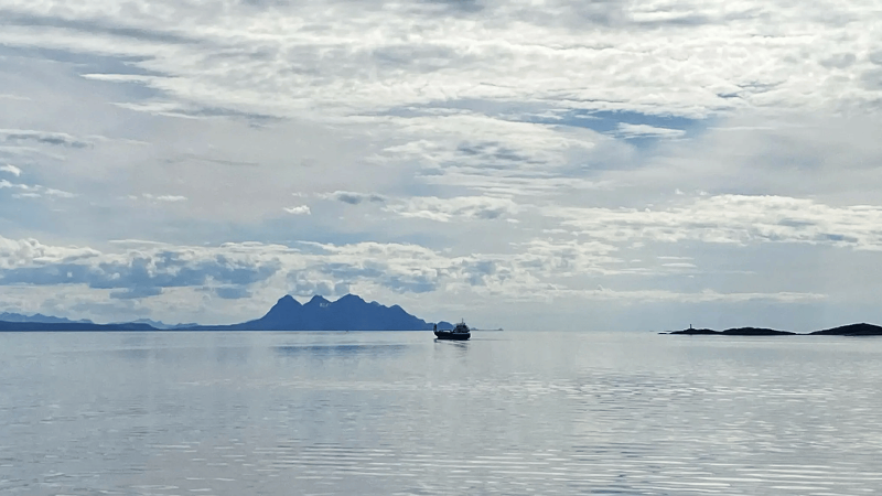 ocean with a boat and mountains in the background