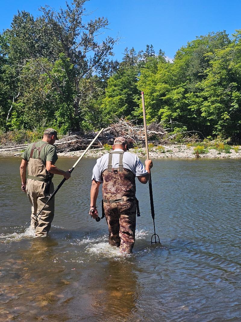 to menn med spyd som skal fiske i en elv