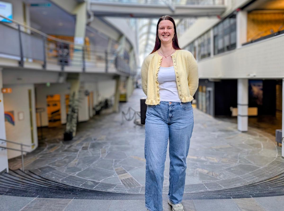 KVinne st&aring;r i trapp og smiler til kamera