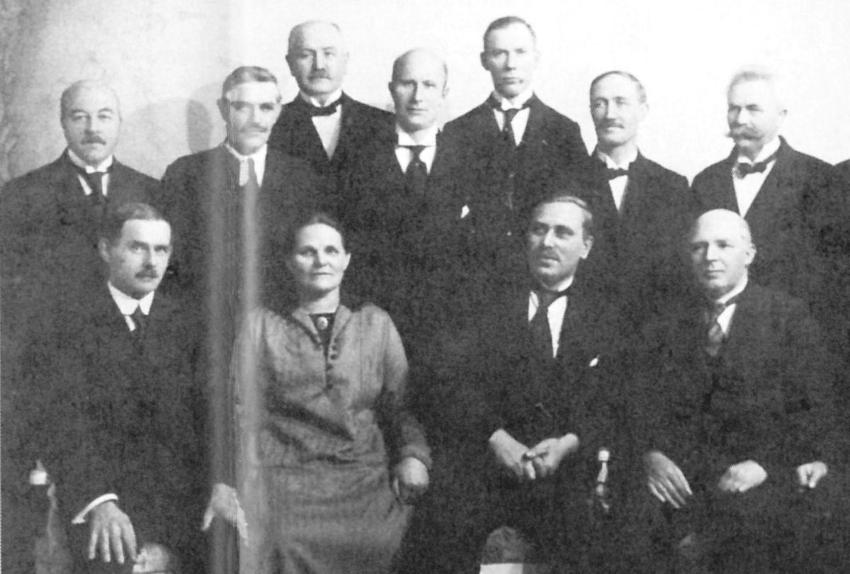 sort-hvitt foto av en gruppe menn og én kvinne som poserer