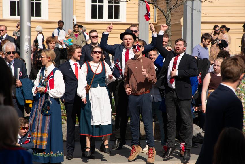 Glade bunad- og dresskledde folk p&aring; 17. mai 