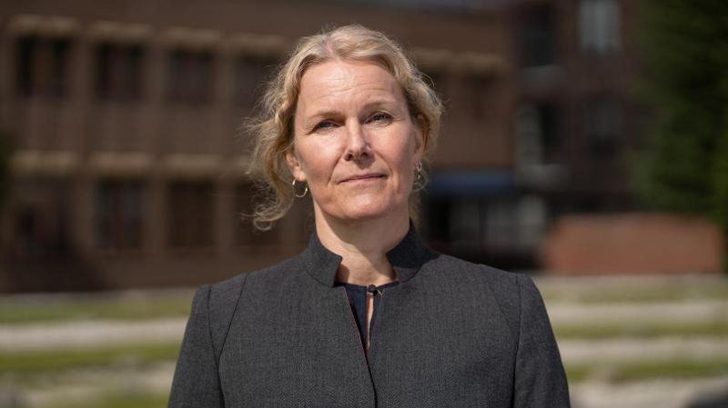 dame som st&aring;r ute foran universitetsbygg