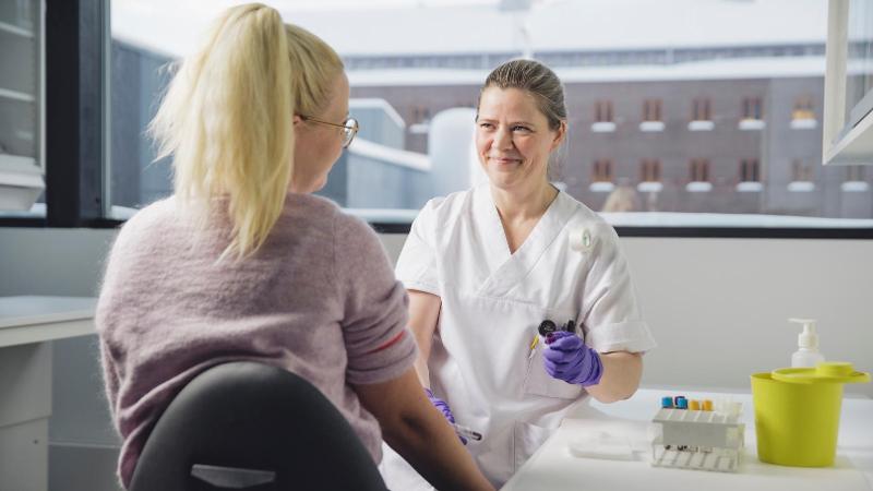 en dame som blir tatt blodpr&oslash;ve av en sykepleier