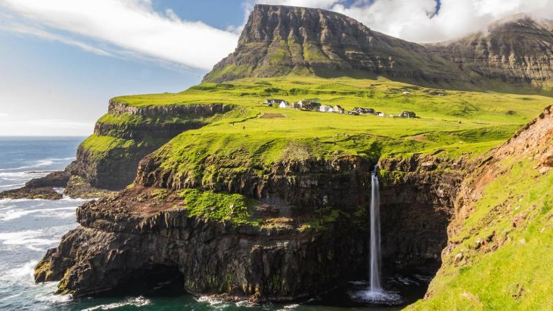 gr&oslash;nt landskap med hav rundt og en foss