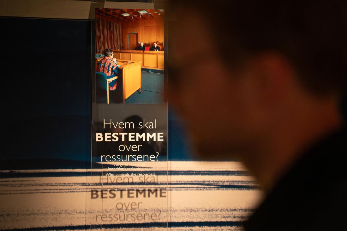 Ansiktet av mann skimtes foran gammelt bilde av rettsak i forbindelse med Alta-saken. 