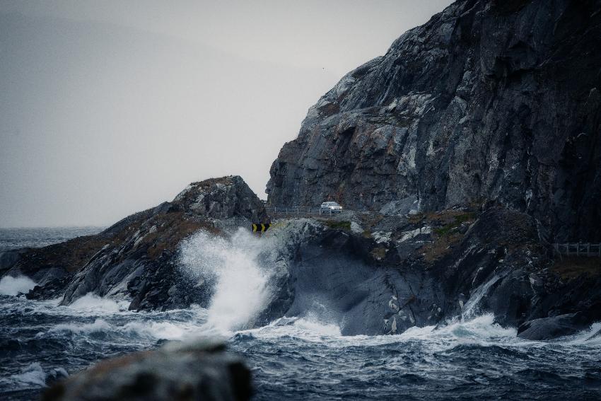 b&oslash;lge som sl&aring;r inn mot land der bil kj&oslash;rer p&aring; en kronglete vei