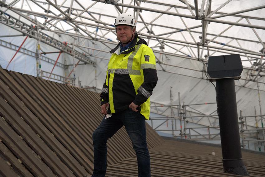 Bildet viser Rune Wara med gul og svart arbeidsjakke og hvit vernehjelm. Han st&aring;r p&aring; taket p&aring; &Aacute;rdna som er omgitt av en hvit duk. 
