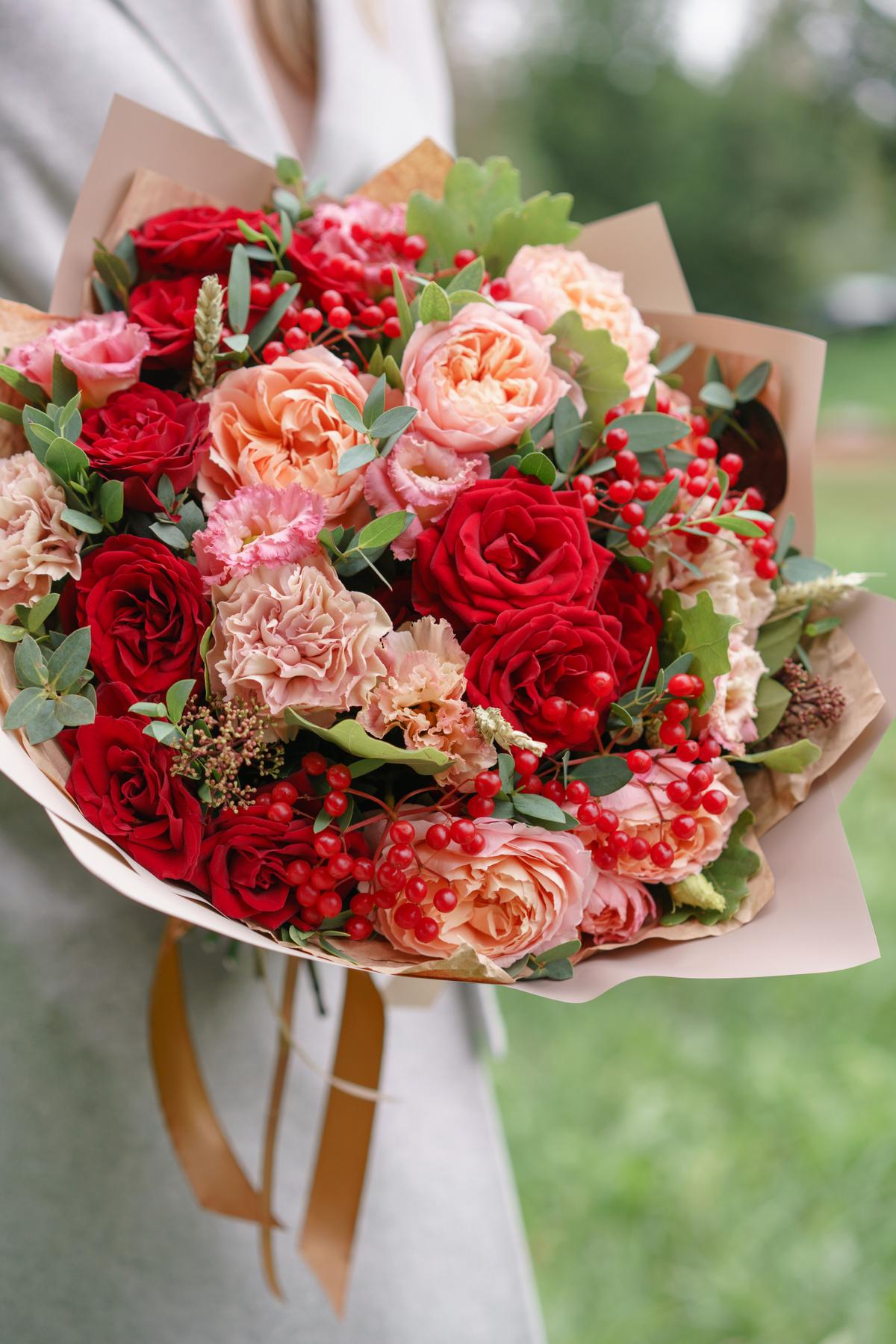 mp27633949-lovely-woman-holding-a-beautiful-autumn-bouquet-flower-arrangement-with-carnations-and-red-garden-roses-color-pink-green-lawn-on-background.jpg