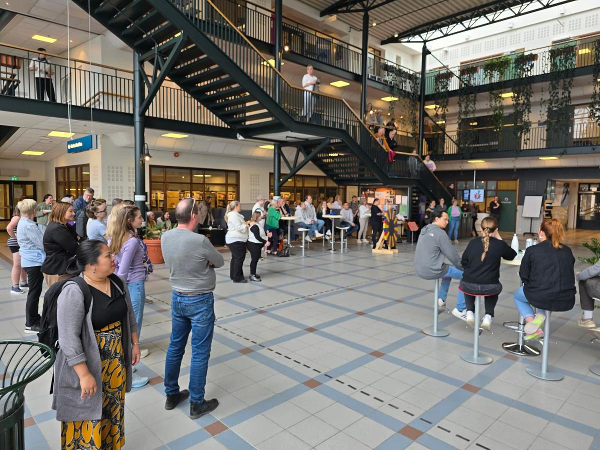 Viser foajeen til universitetet mange personer som st&aring;r samlet her og der. 