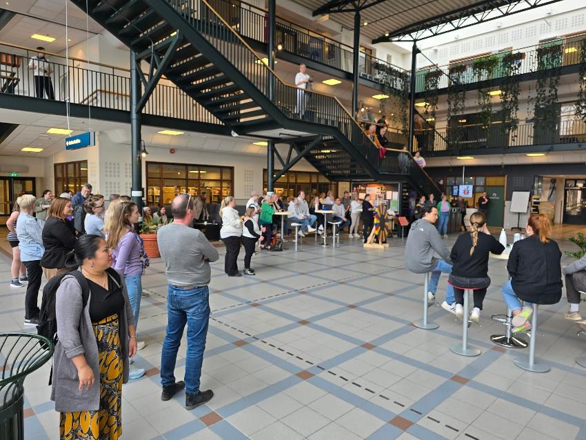 Viser foajeen til universitetet mange personer som står samlet her og der. 