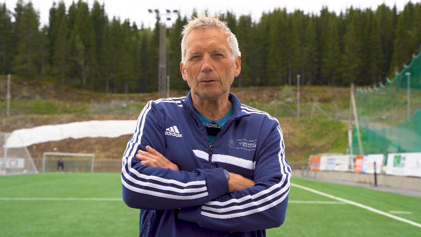 Mann snakker om fotball p&aring; gressmate. 