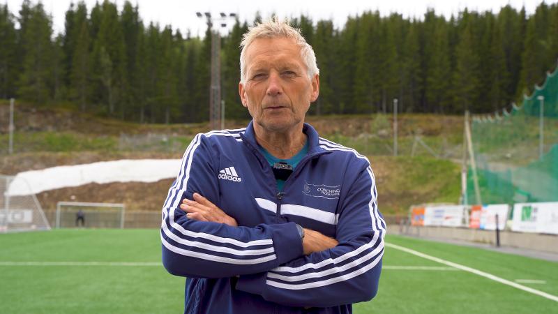 Mann forteller om fotball p&aring; gressmatta. 