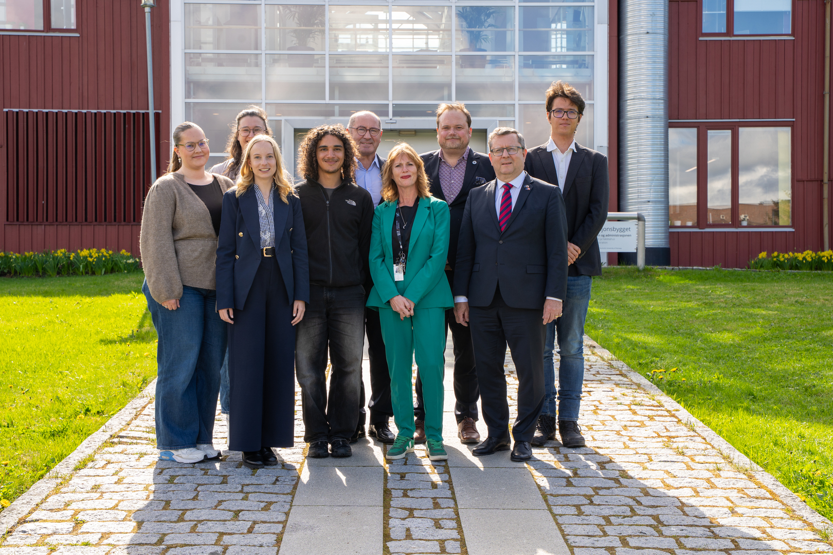 Gruppefoto ved en plen og stor bygning.
