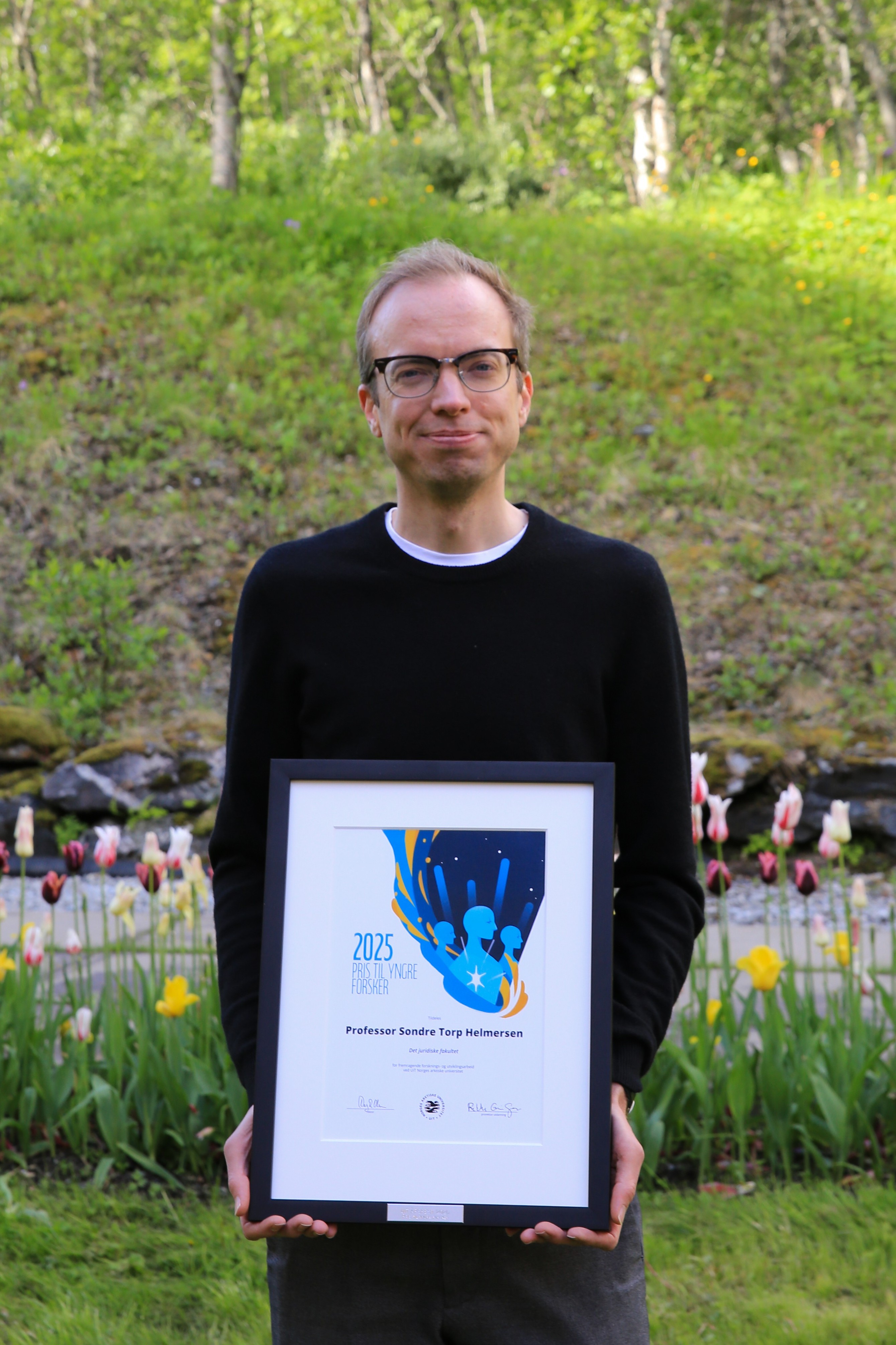 mann, svart geser, har briller, holder diplom, gr&oslash;nn, naturbakgrunn, tulipaner, gress, tr&aelig;r